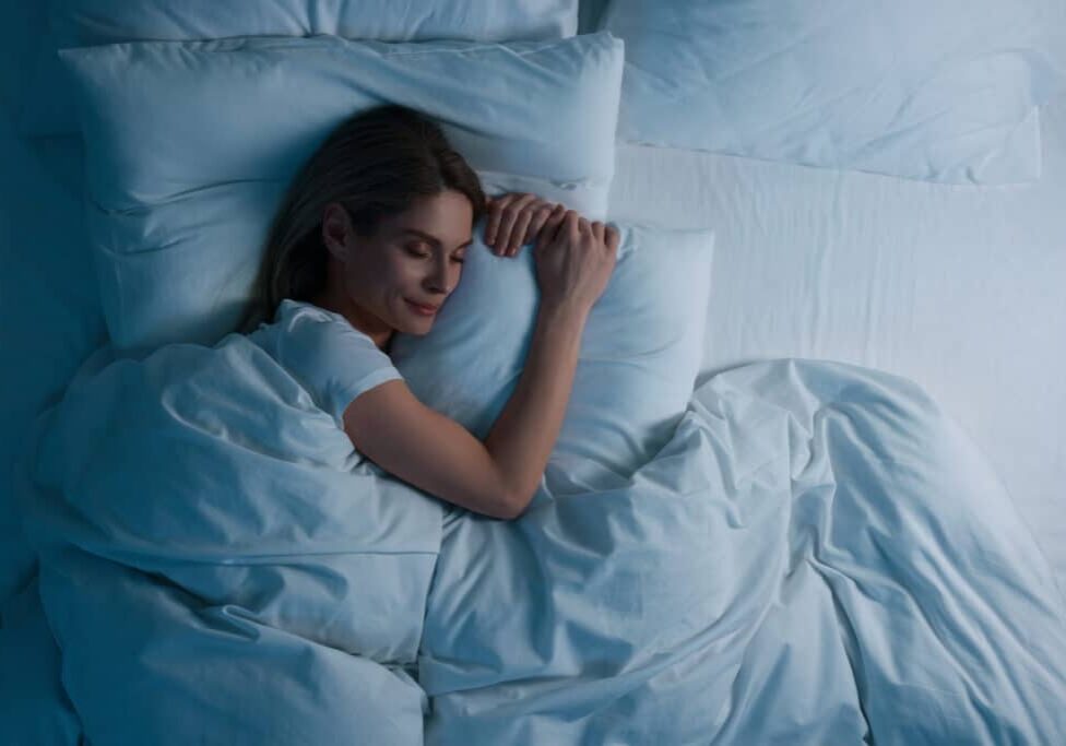 Woman sleeping in bed at night, above view. Space for text